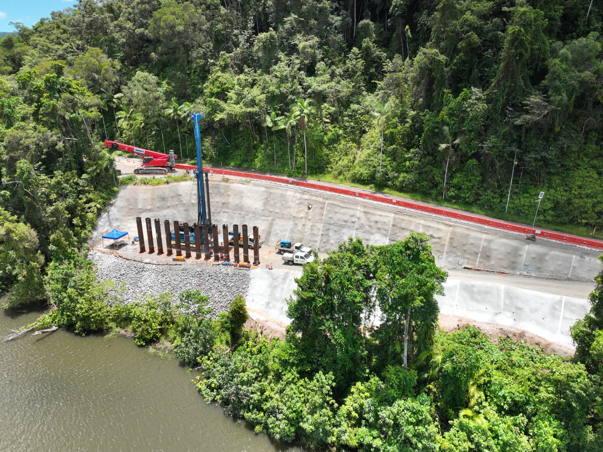 Aerial view of a North Queensland civil construction site with piling equipment and surrounding rainforest